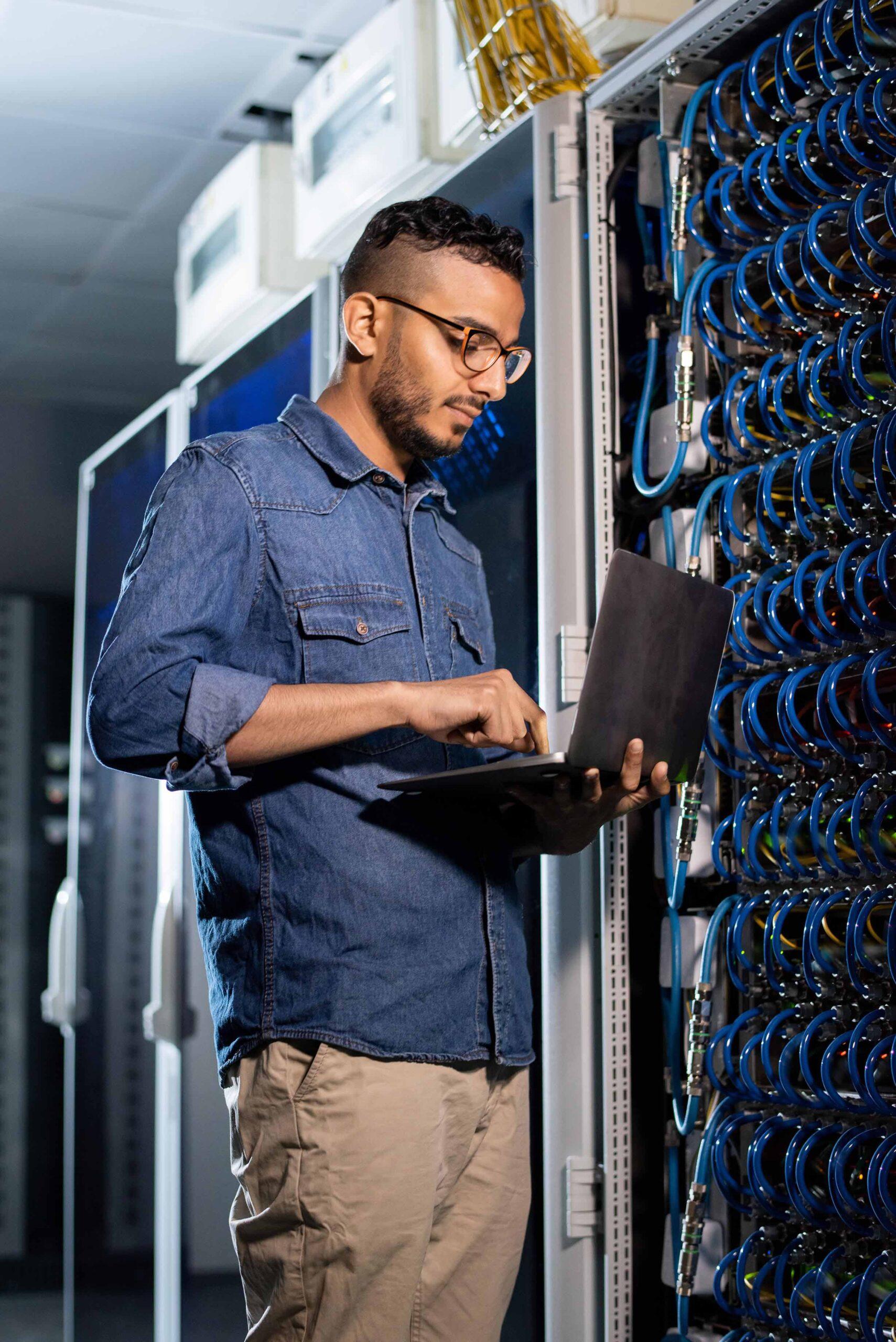 Network specialist working on a laptop in a data center