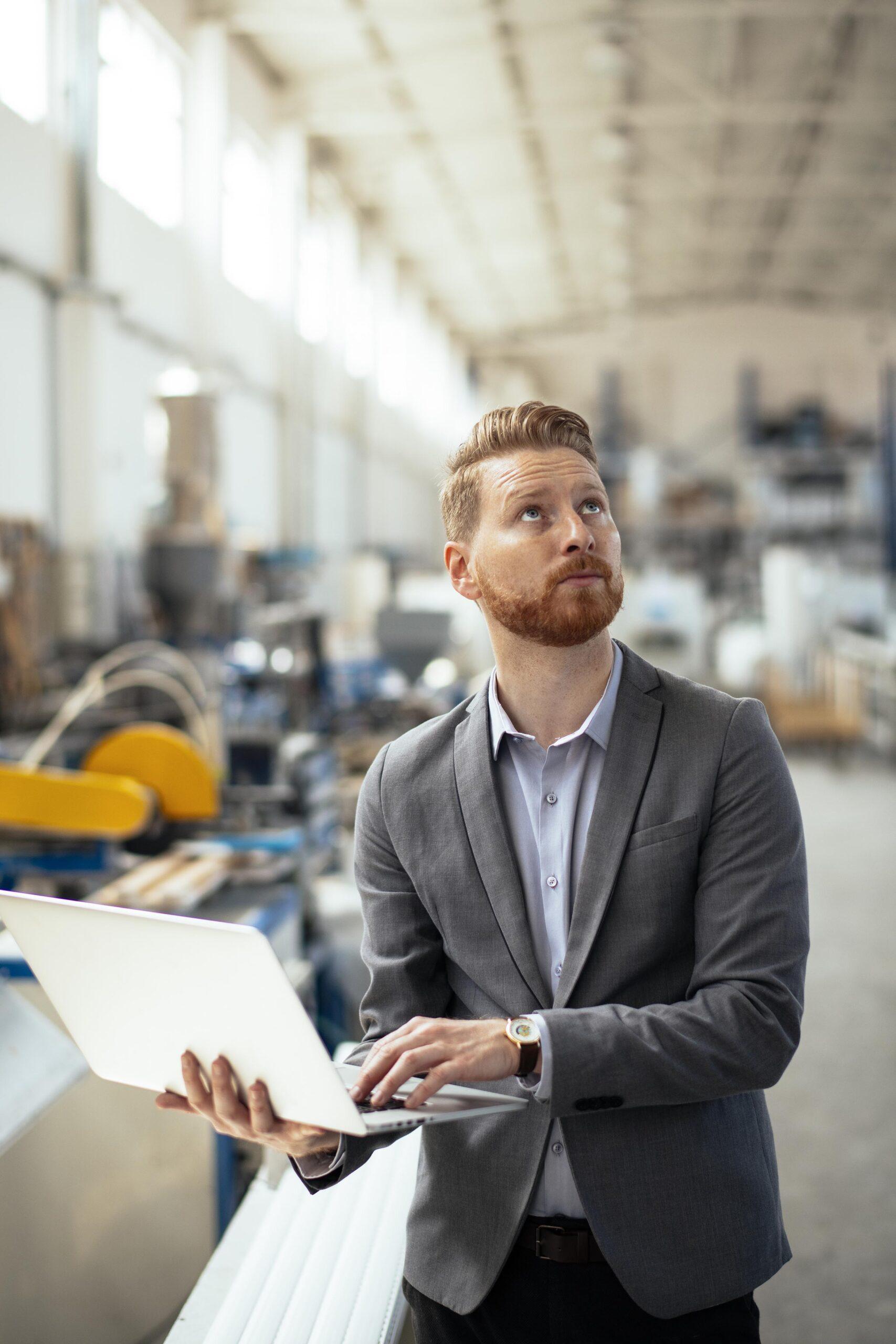 IT engineer holding laptop and examining factory floor